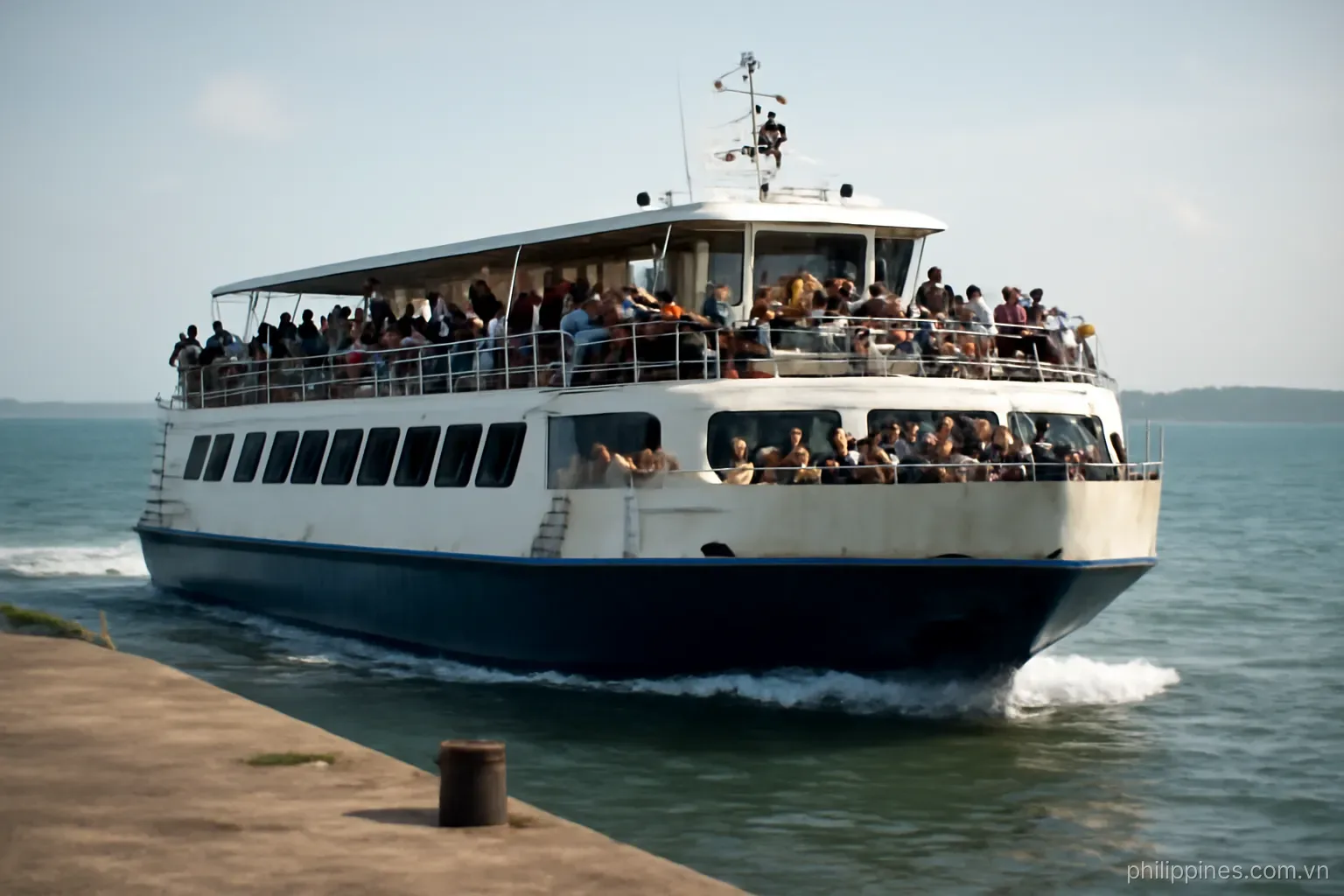 A crowded inter-island ferry pulling away from a concrete pier with passengers on the upper deck, no readable text